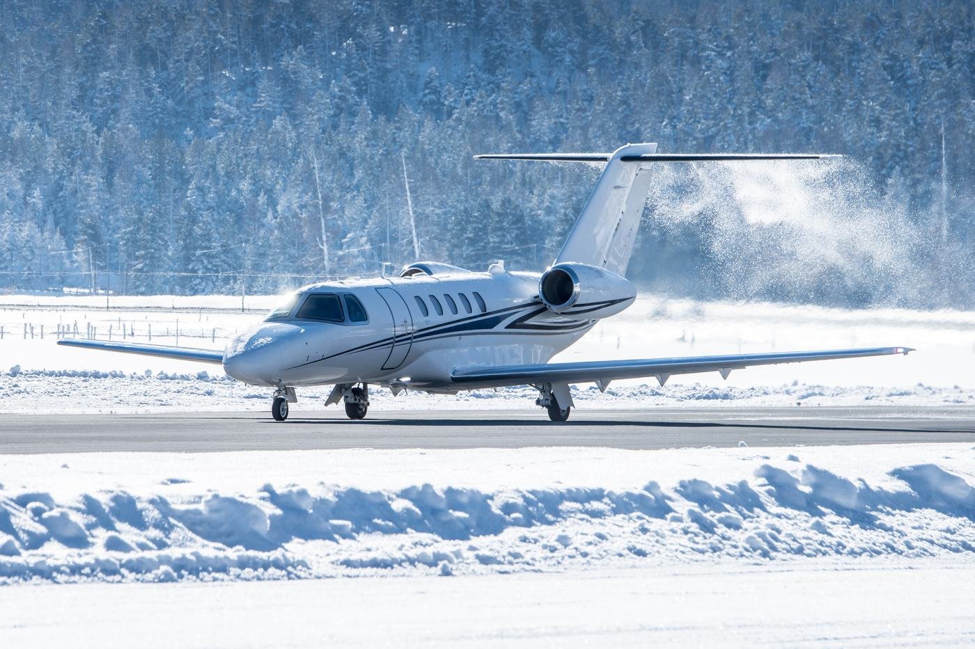 A private jet on a cleared runway surrounded by snow and winter forest