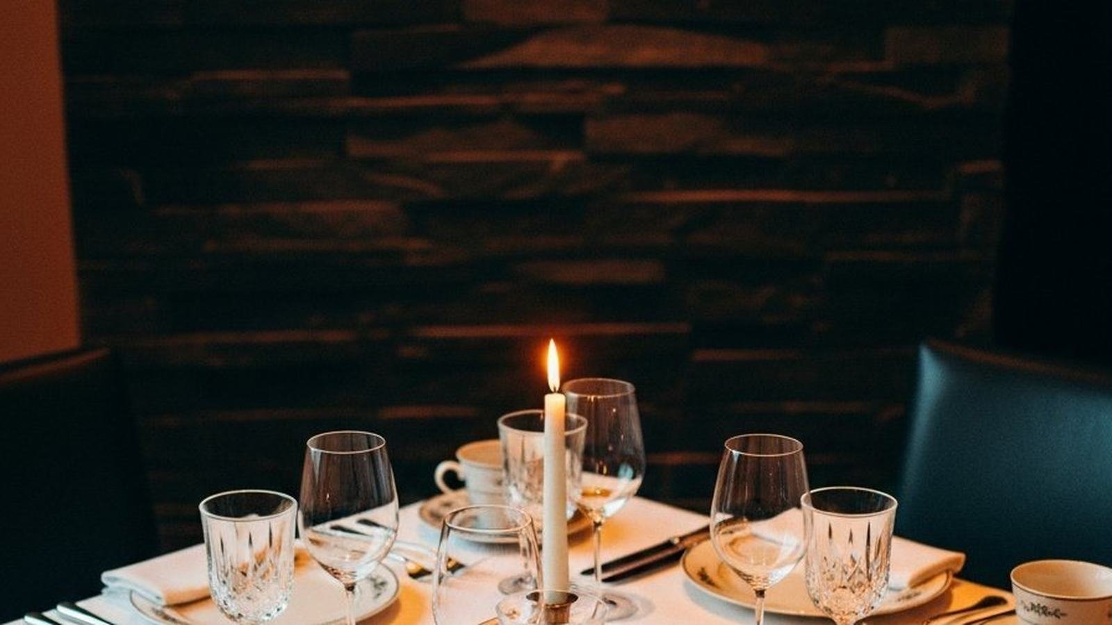 A candlelit table set for dinner against a stone wall