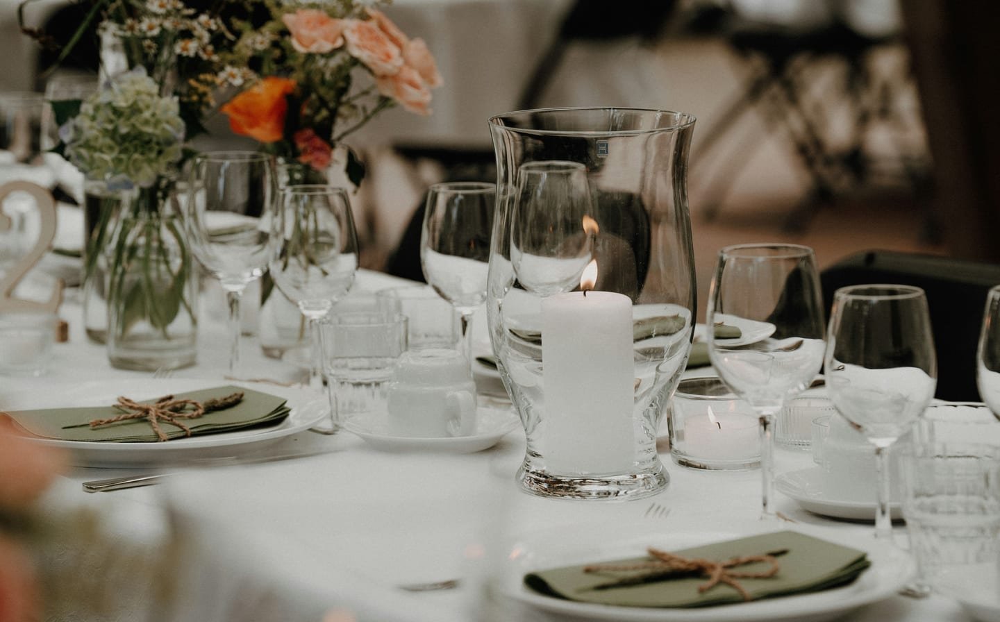 A candlelit table with white linen and flowers, illustrating a private dinner