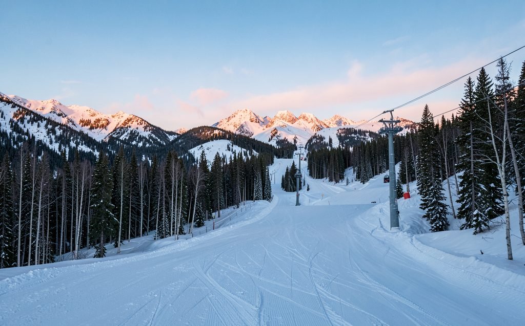Freshly groomed runs and an empty chairlift on a Colorado ski mountain at sunrise