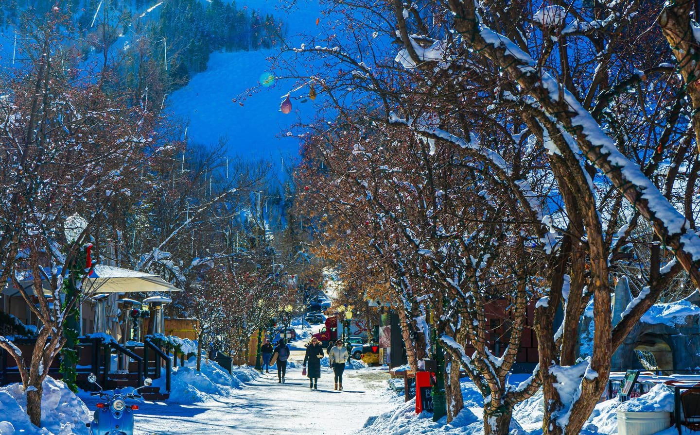 Downtown Aspen at dusk in winter, shop windows lit and snow on the street