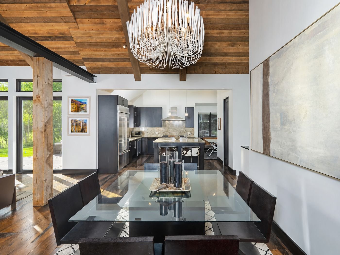 The formal dining table under a sculptural chandelier, with the kitchen visible beyond