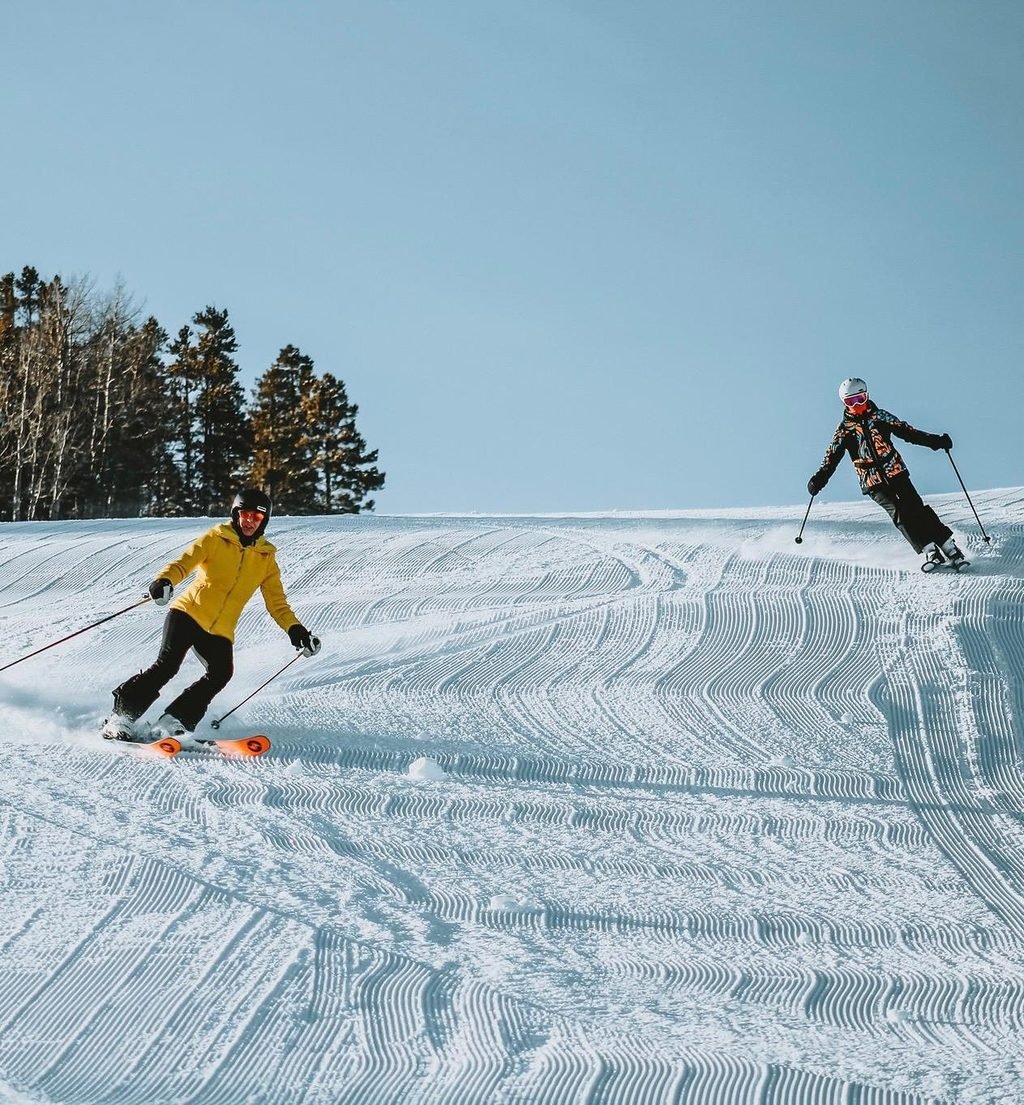 Two skiers on a groomed run above Aspen
