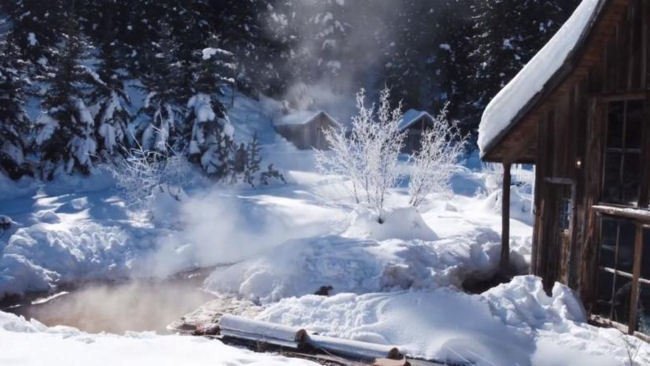 Luxury hot springs in the middle of a snowy forest with steam rising