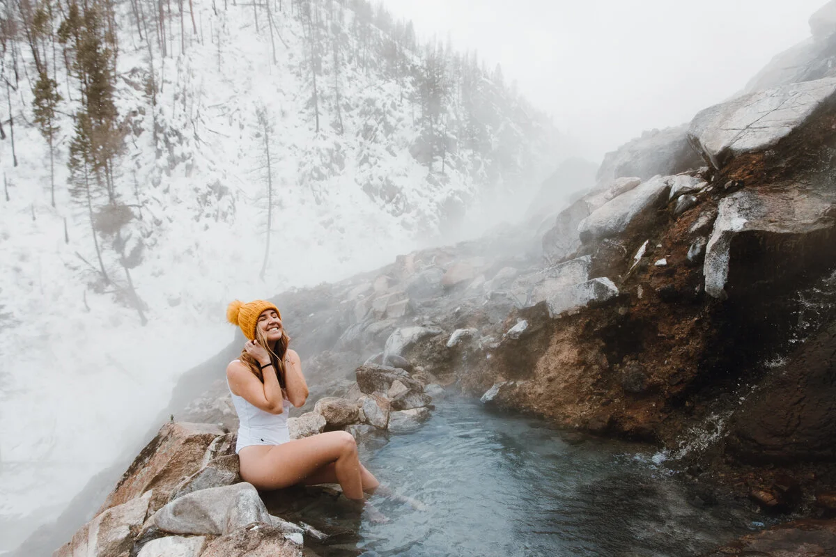 Woman relaxing in a natural hot spring surrounded by snow in Aspen