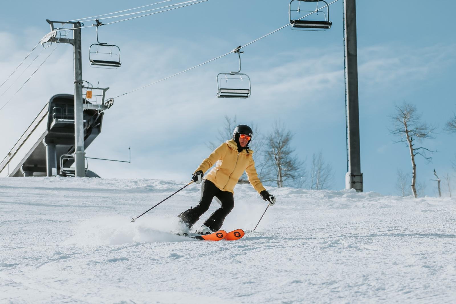 Luxury skier descending the Aspen slopes under blue skies during a private guided day by Aspen Privé